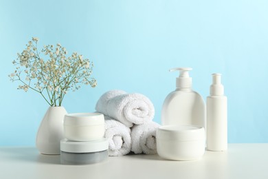 Photo of Different bath accessories and gypsophila on white table against light blue background