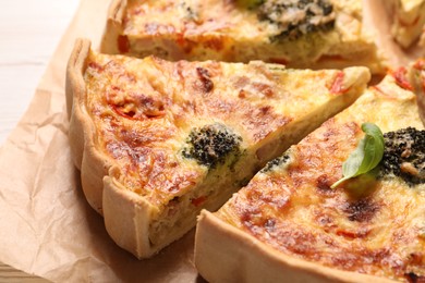 Photo of Delicious homemade vegetable quiche on parchment paper, closeup