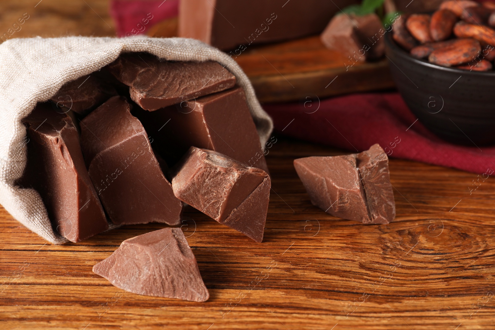 Photo of Pieces of tasty milk chocolate on wooden table, closeup