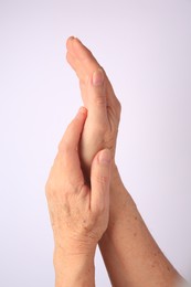 Closeup view of older woman's hands on white background