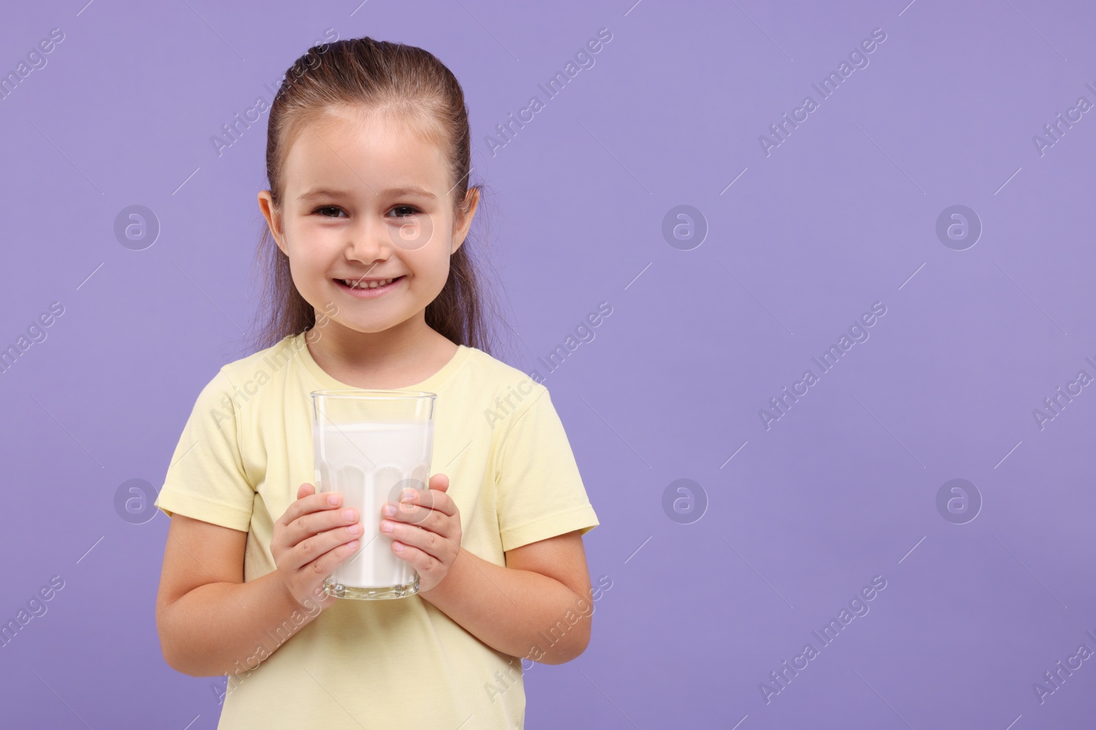 Photo of Cute girl with glass of fresh milk on violet background, space for text