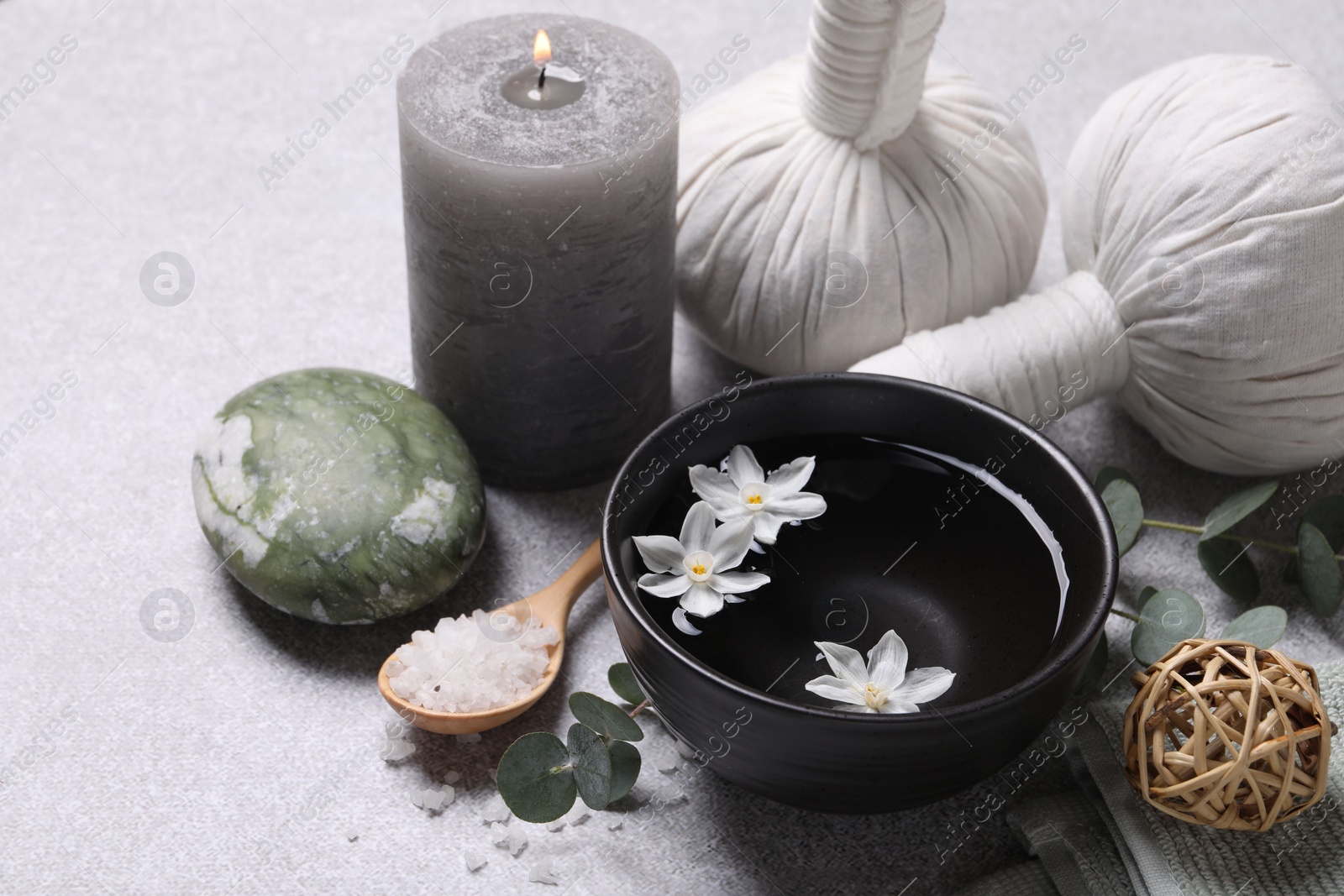 Photo of Beautiful composition with herbal massage bags, spa products and flowers on light grey table