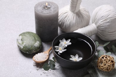 Beautiful composition with herbal massage bags, spa products and flowers on light grey table