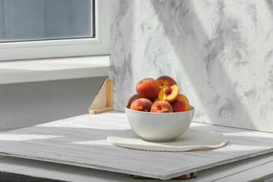 Photo of Bowl of juicy peaches and double-sided backdrop on table in photo studio. Space for text