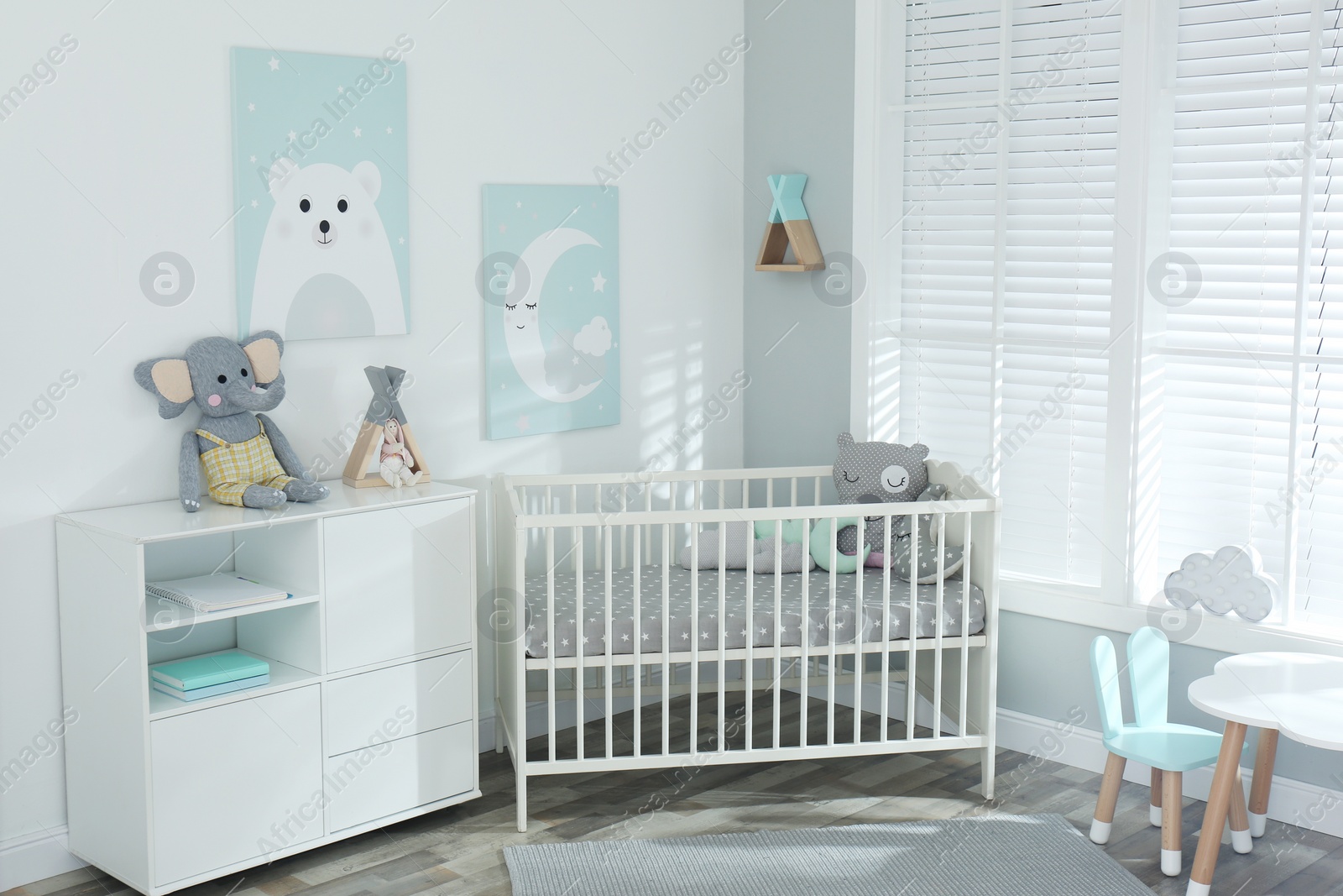 Photo of Stylish baby room interior with crib and cute pictures on wall