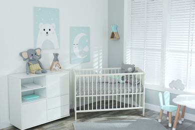 Photo of Stylish baby room interior with crib and cute pictures on wall