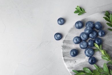 Flat lay composition with tasty blueberries on grey table, space for text