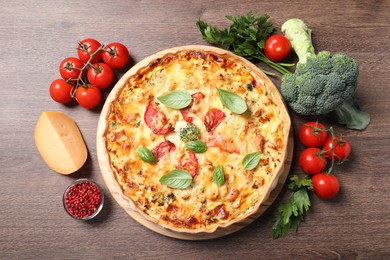 Photo of Tasty cheese quiche and ingredients on wooden table, flat lay