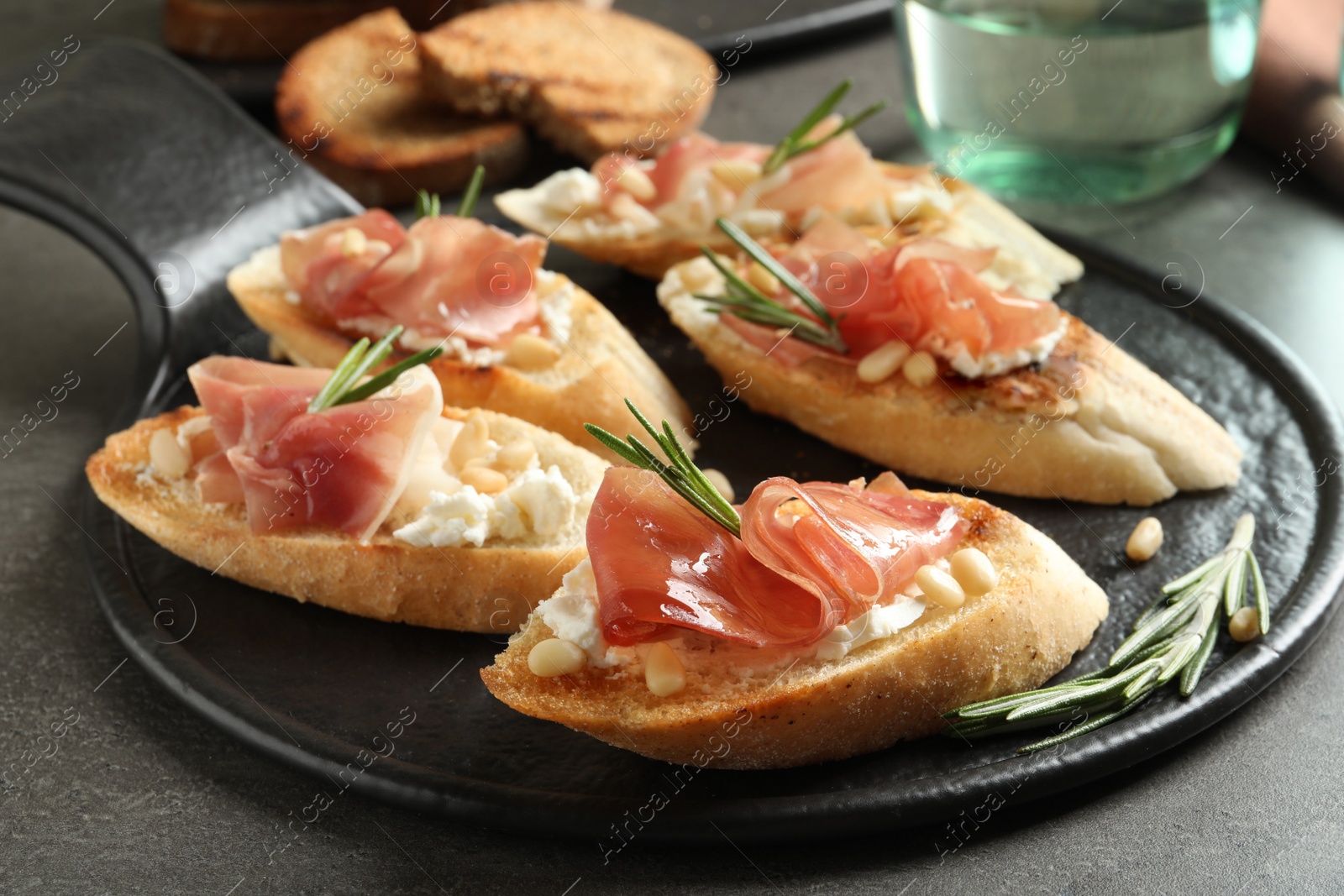 Photo of Tasty bruschettas with prosciutto and cream cheese served on table, closeup