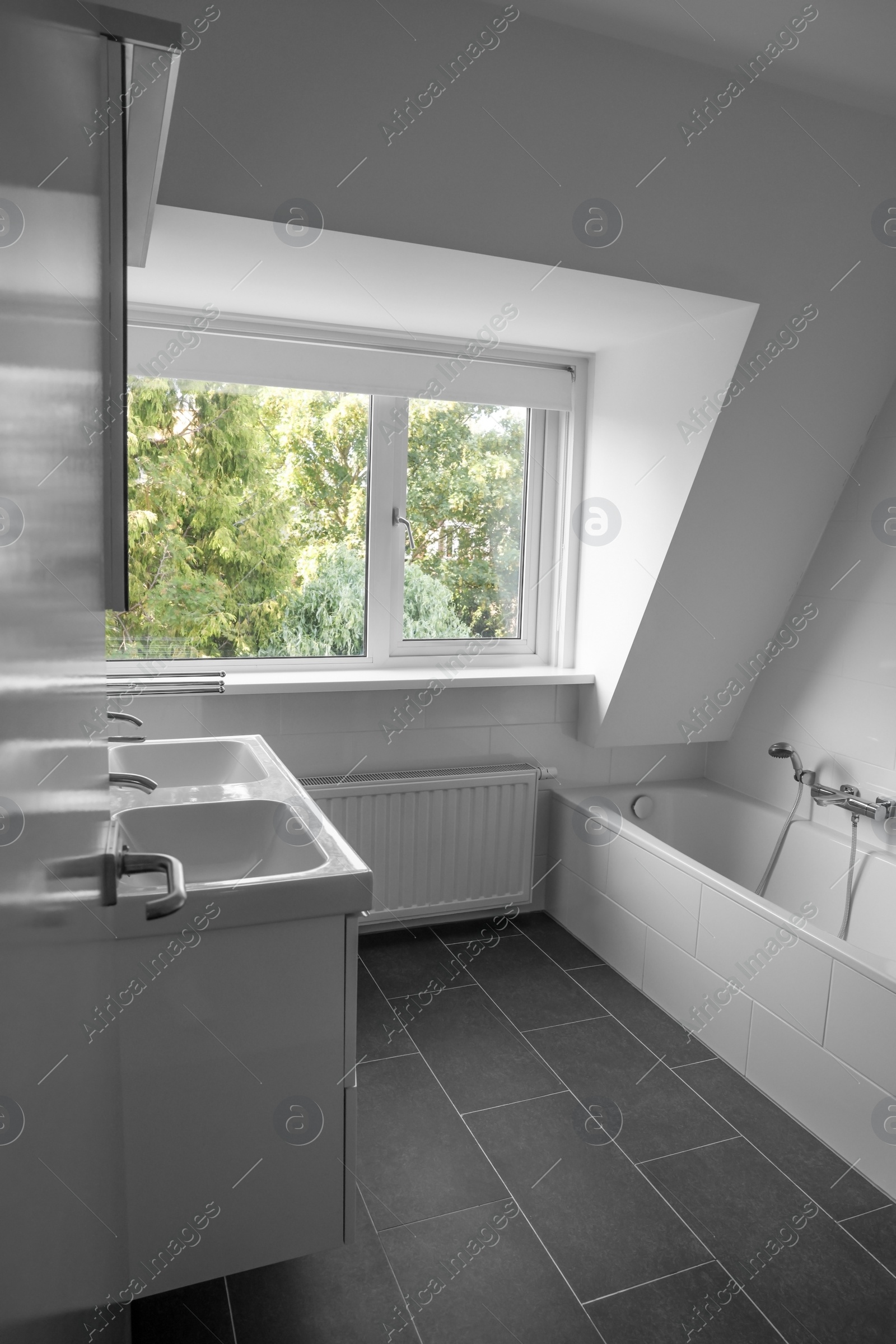 Photo of Stylish bathroom interior with tub and sinks near window