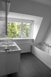 Stylish bathroom interior with tub and sinks near window