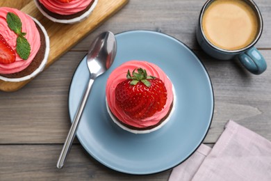 Photo of Sweet cupcake with fresh strawberry served on wooden table, flat lay