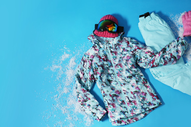 Photo of Stylish winter sport clothes on light blue background, flat lay. Space for text