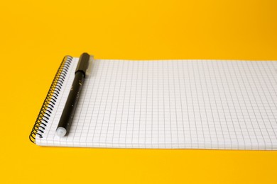 Notepad with erasable pen on yellow background, closeup