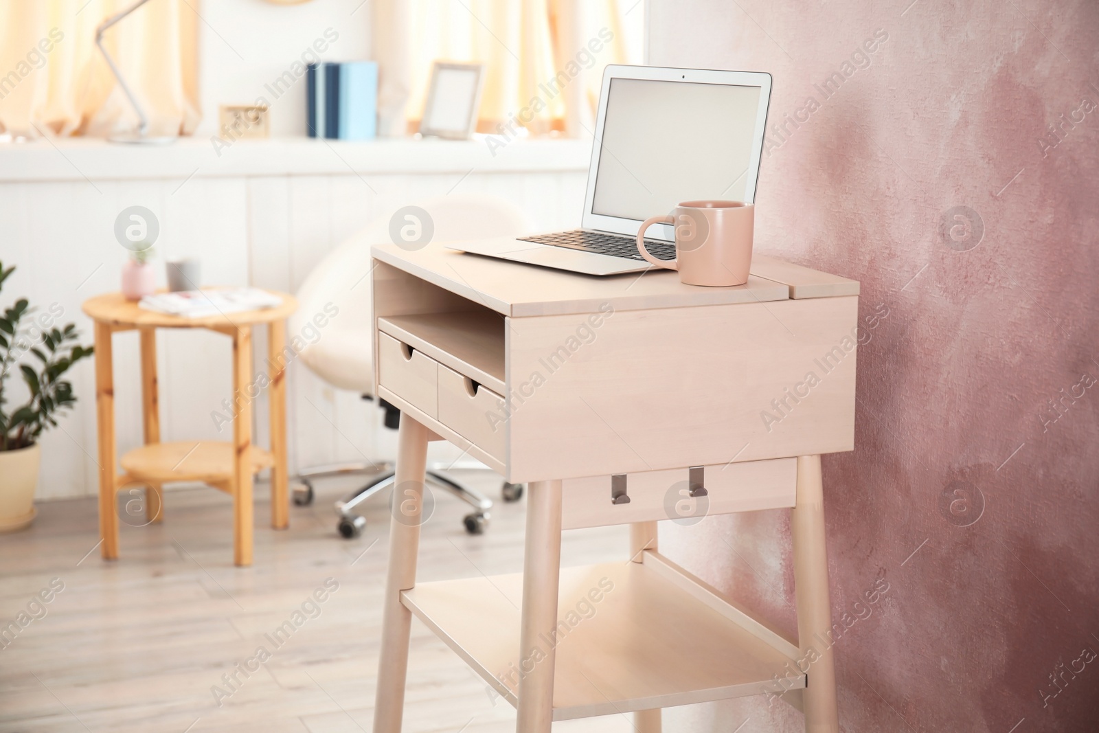 Photo of High wooden table with laptop as stand up workplace in modern interior