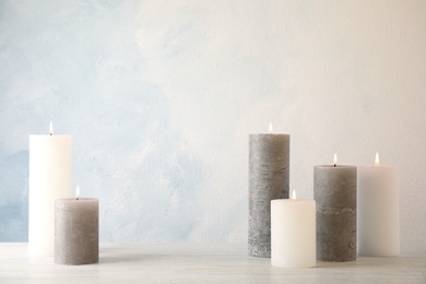 Photo of Burning candles on table against light background. Space for text