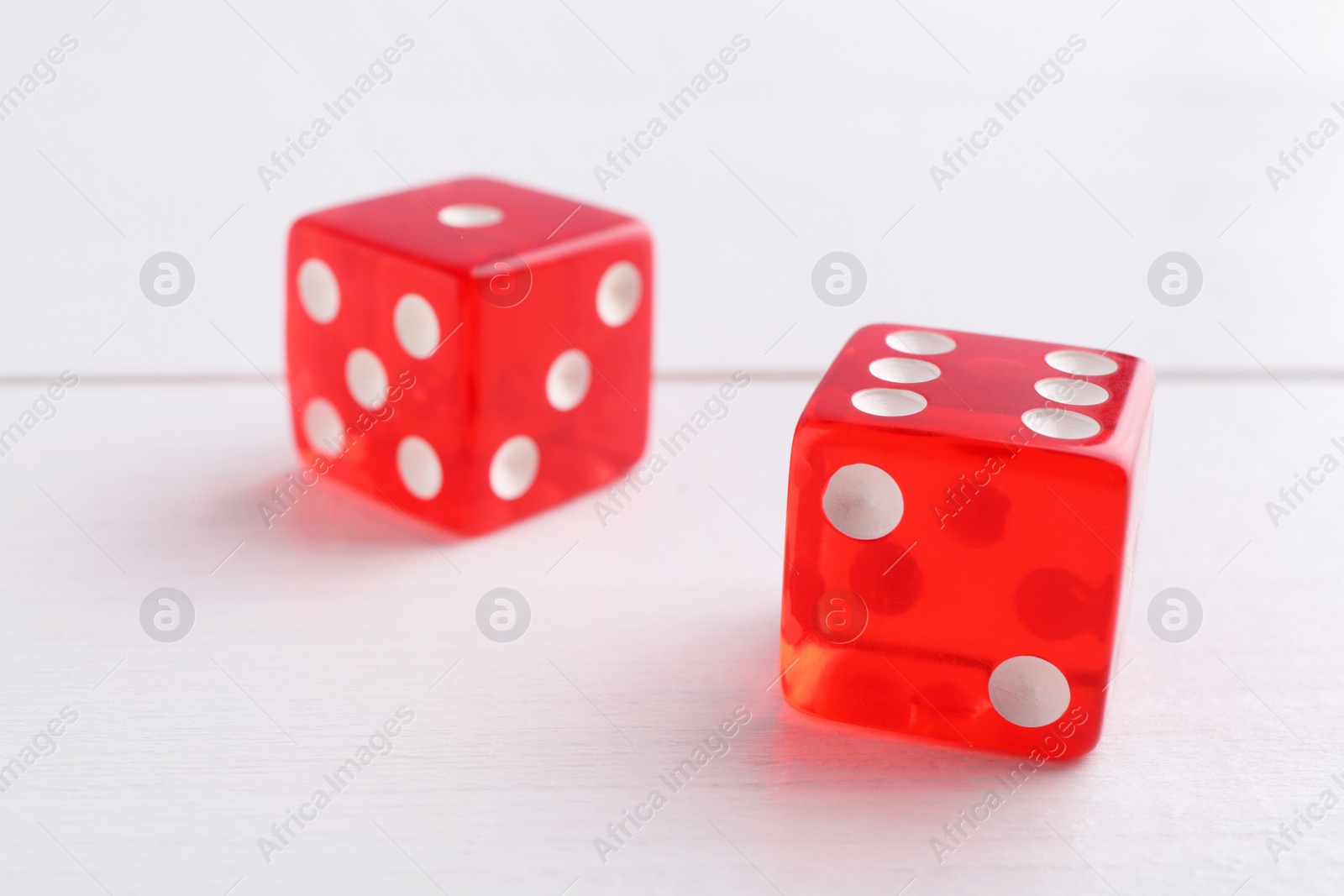 Photo of Two red game dices on white wooden table, closeup