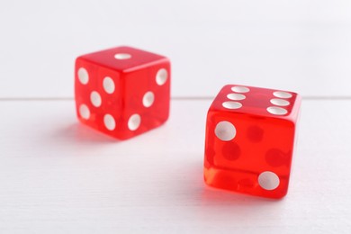 Photo of Two red game dices on white wooden table, closeup