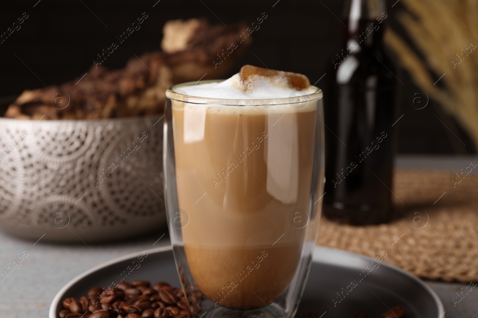 Photo of Glass of aromatic coffee with syrup and beans on plate, closeup