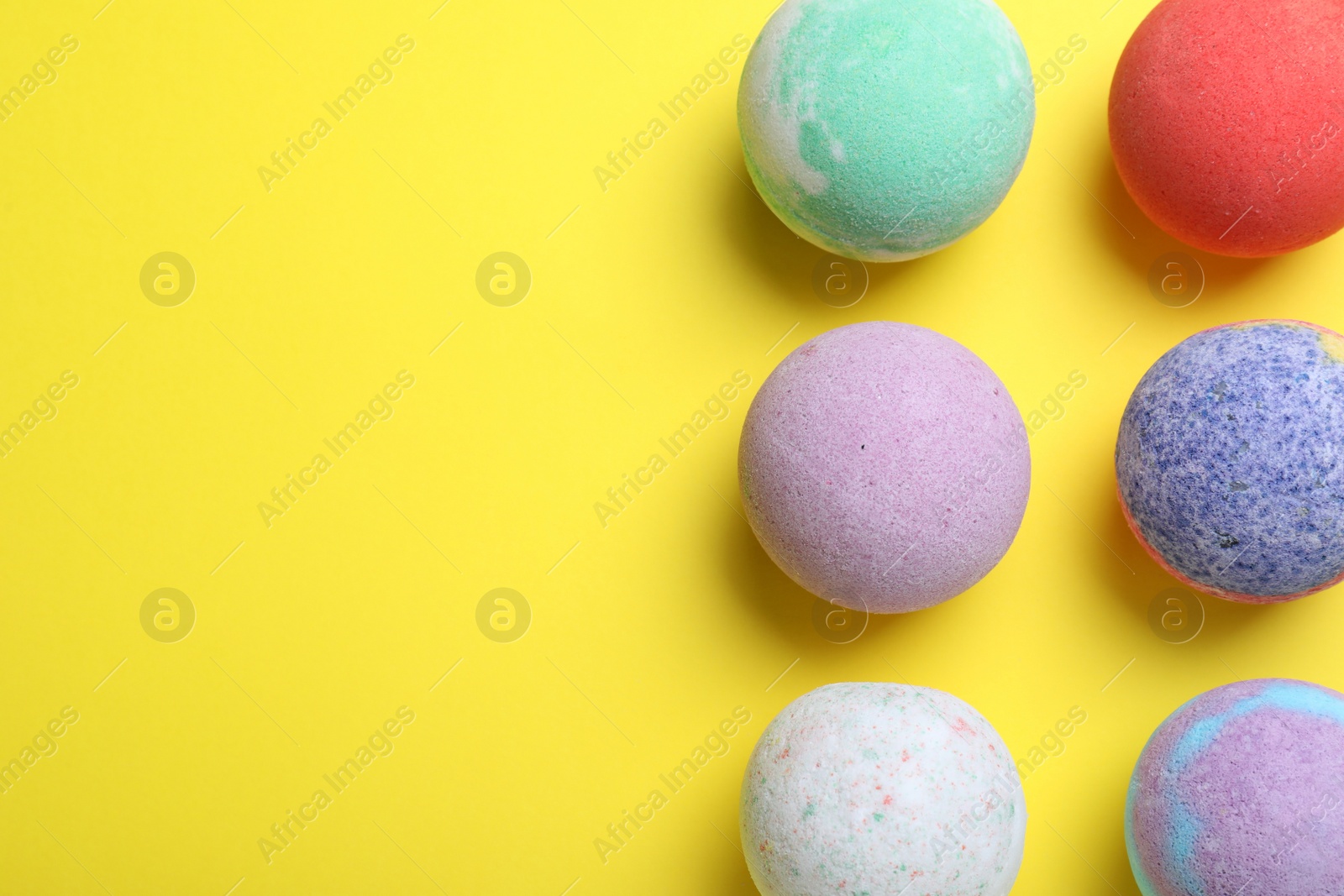 Photo of Colorful bath bombs on yellow background, flat lay. Space for text