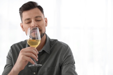 Man with glass of delicious wine indoors