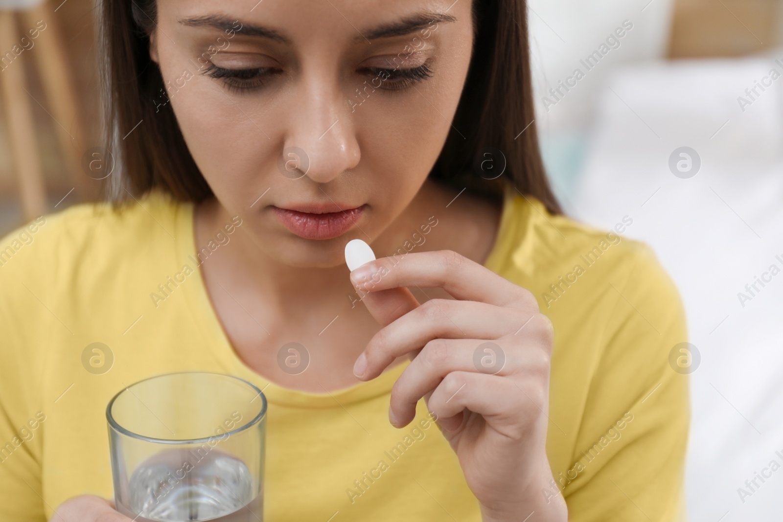 Photo of Young woman taking abortion pill on blurred background, closeup