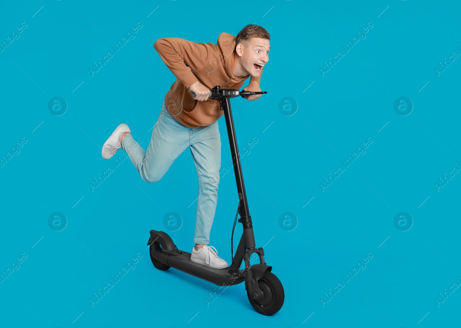 Photo of Emotional man riding modern electric kick scooter on light blue background