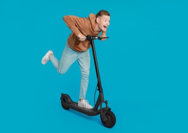 Emotional man riding modern electric kick scooter on light blue background