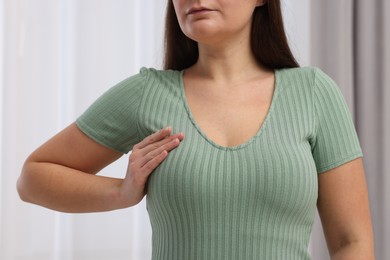 Photo of Mammology. Woman doing breast self-examination indoors, closeup