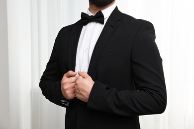 Photo of Man in suit, shirt and bow tie indoors, closeup