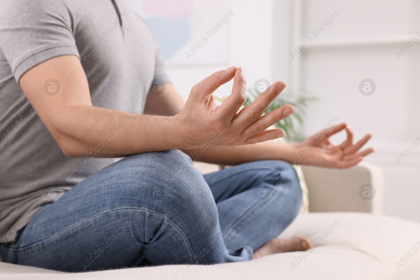 Photo of Man meditating on sofa at home, closeup. Harmony and zen