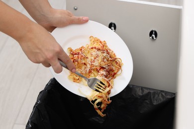 Woman throwing pasta into bin indoors, closeup