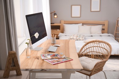 Comfortable workplace with modern computer near window in bedroom. Interior design