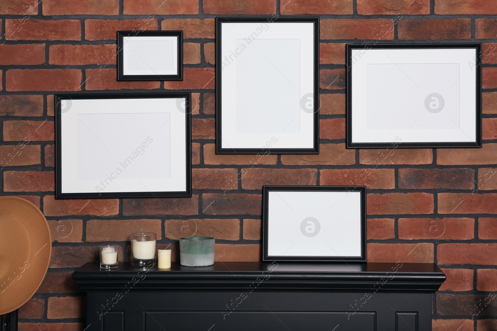 Photo of Empty frames and scented candles on fireplace indoors