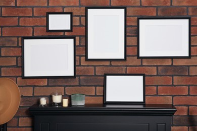 Photo of Empty frames and scented candles on fireplace indoors