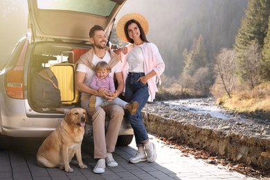 Photo of Parents, their daughter and dog near car outdoors, space for text. Family traveling with pet