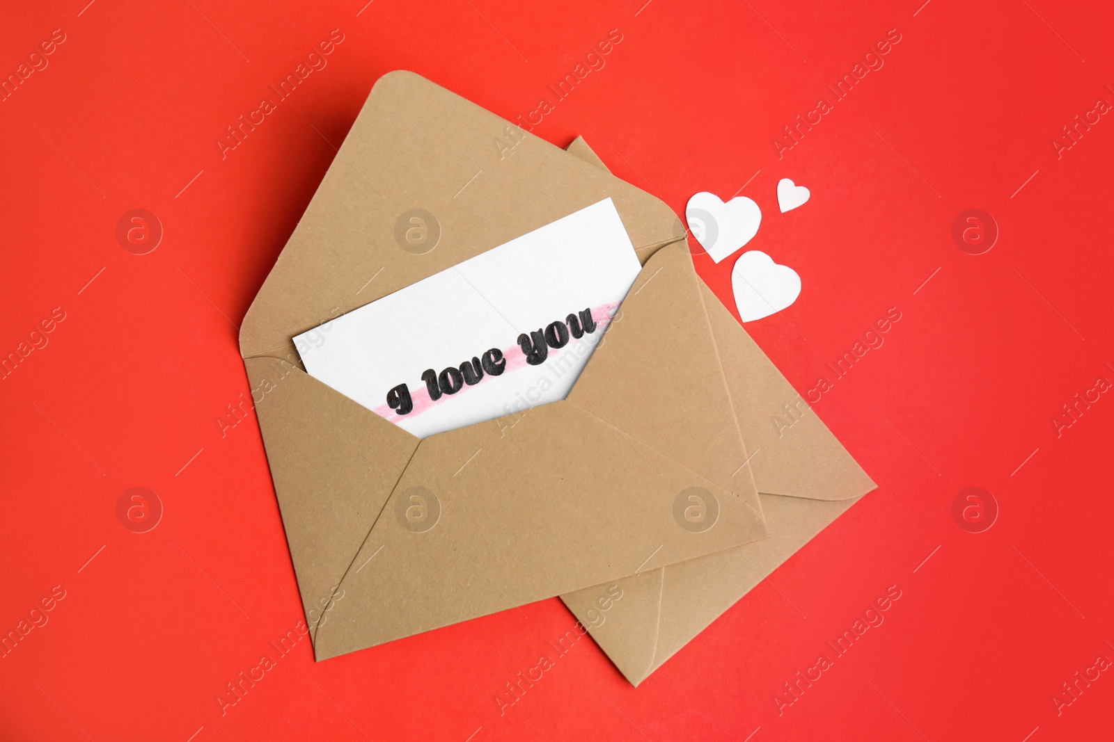 Photo of Card with phrase I Love You in envelope and paper hearts on red background, flat lay
