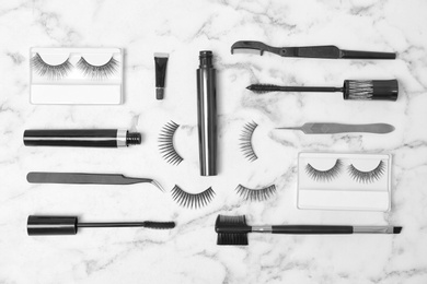 Photo of Flat lay composition with false eyelashes and cosmetic tools on light background