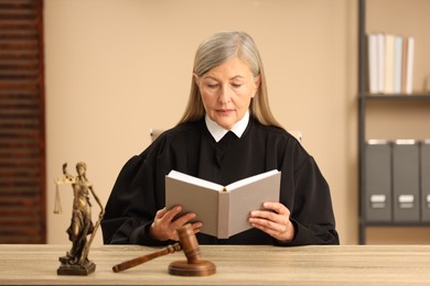 Photo of Judge reading book at wooden table indoors
