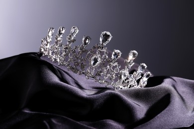 Photo of Beautiful silver tiara with diamonds on dark cloth against grey background