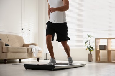 Photo of Sporty man training on walking treadmill at home, closeup