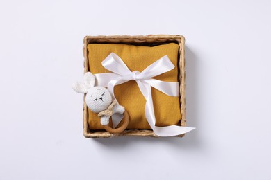 Photo of Baby accessory. Rattle and child`s clothes in wicker box on white background, top view