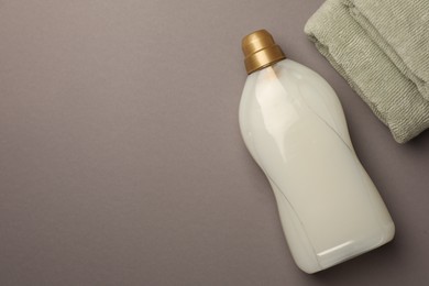 Photo of Bottle of fabric softener and terry towels on gray background, flat lay. Space for text