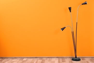 Stylish lamp on floor near color wall. Space for text