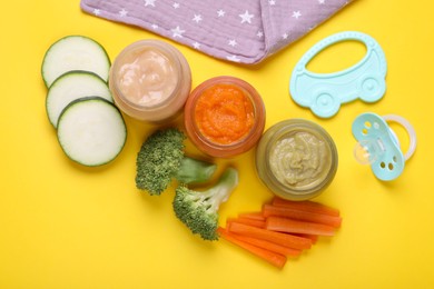 Flat lay composition with glass jars of healthy baby food and vegetables on yellow background