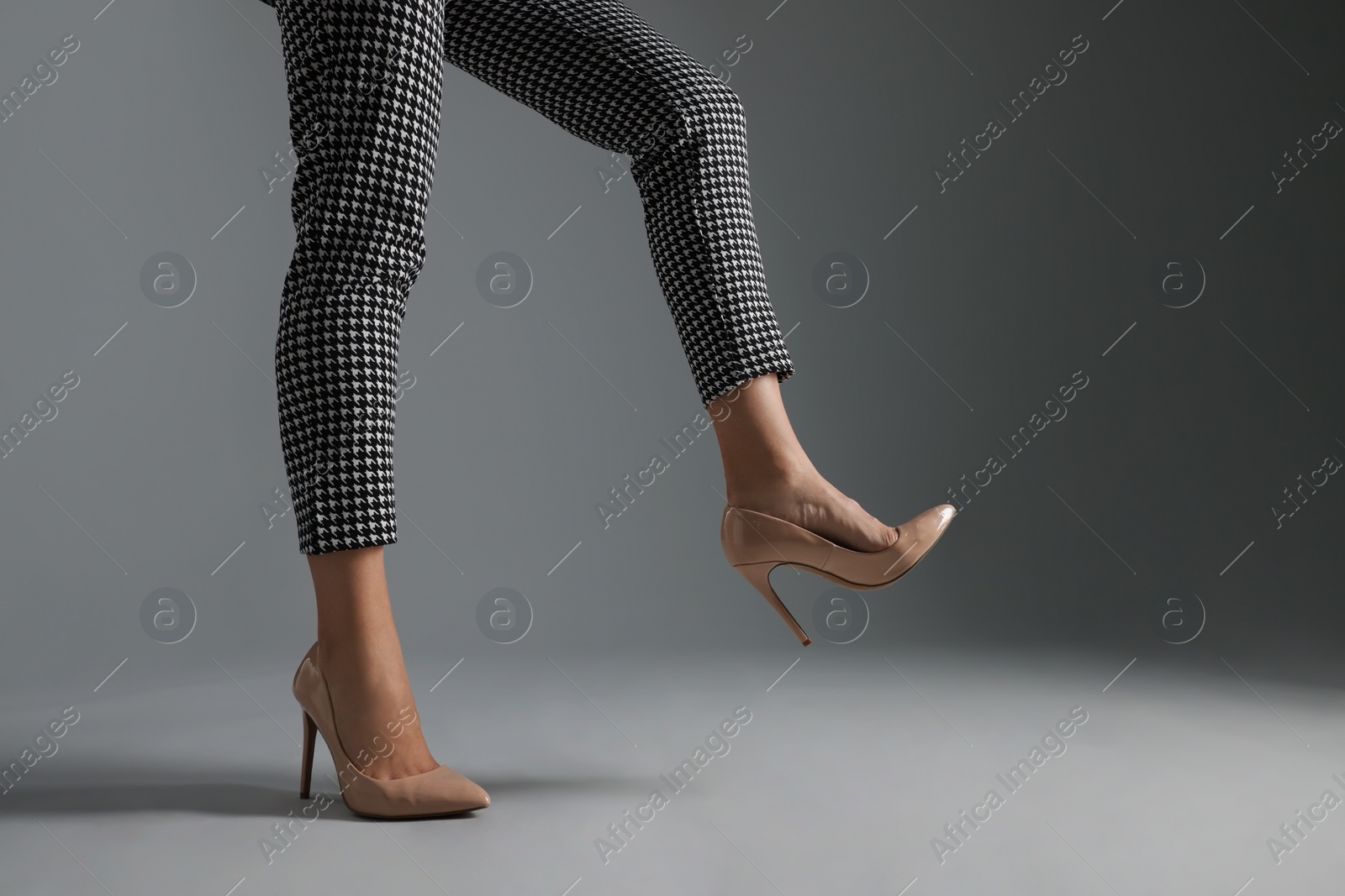 Photo of Businesswoman in beige shoes on grey background, closeup