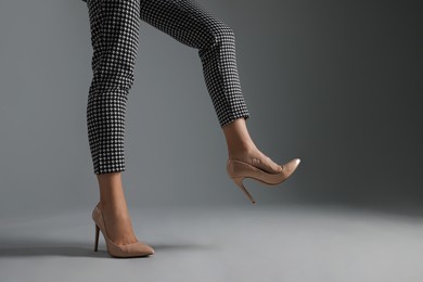 Photo of Businesswoman in beige shoes on grey background, closeup