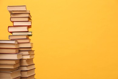 Photo of Many hardcover books on orange background, space for text. Library material