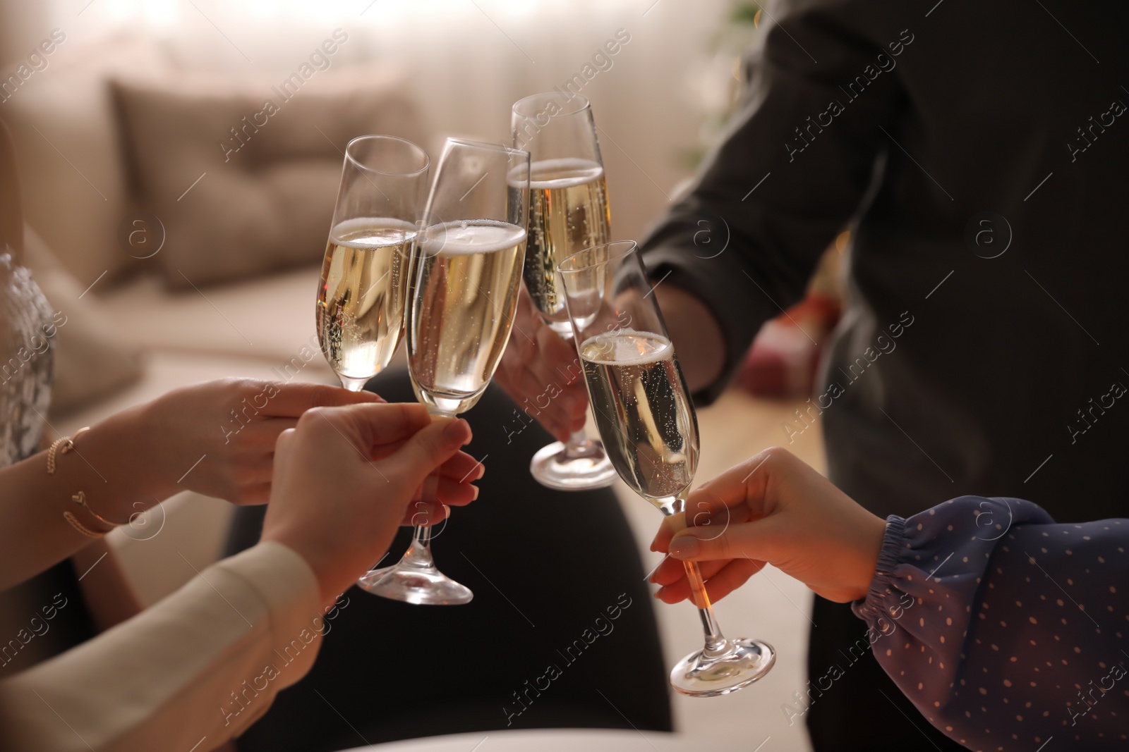 Photo of People clinking glasses with champagne at home, closeup