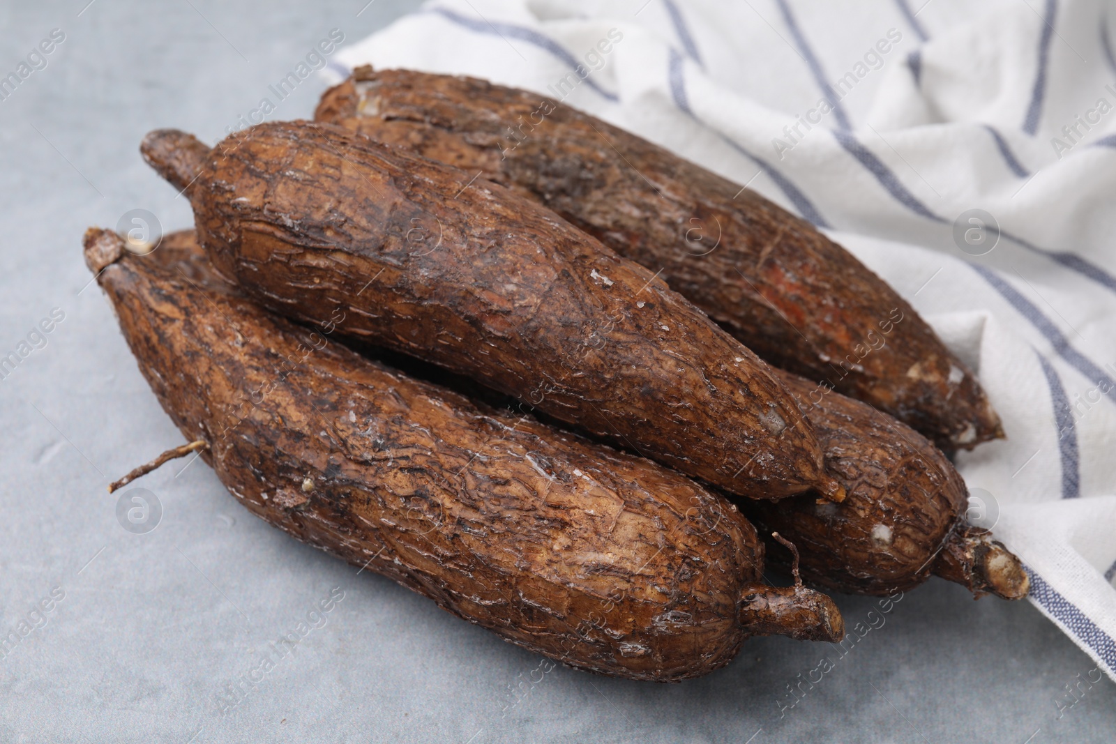 Photo of Fresh whole cassava roots on grey table, closeup